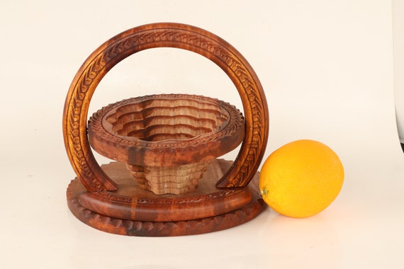 A single piece of wood turned into a collapsible spiral-cut basket — it collapses flat and expands into a functional bowl, which is genuinely clever woodworking craft.