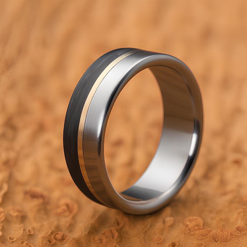 Handmade titanium carbon fiber ring with brass inlay, showing polished silver band and matte black carbon texture