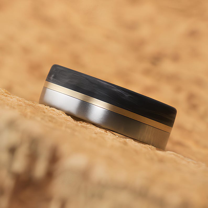 Unique carbon fiber wedding band with titanium and brass inlay, ideal for engraving, upright product photo