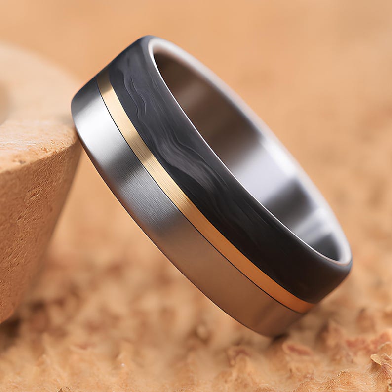 Men's black carbon fiber ring with polished titanium edge and gold brass inlay, angled side view
