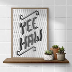 May include: A framed print featuring a black and white mosaic design of the words "Yee Haw" on a white background.