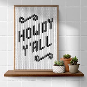 May include: A framed print with a white background and black hexagonal tiles spelling out "Howdy Y'all" in a stylized font.
