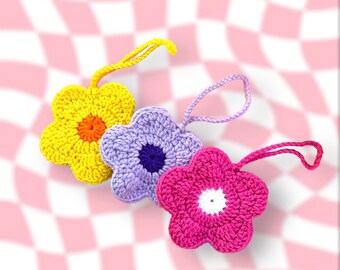 May include: Three crocheted flower-shaped ornaments in yellow, purple, and pink. Each flower has a smaller circle in the center.