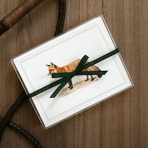 Puede incluir: Un juego de tarjetas de felicitaci&oacute;n en blanco con una ilustraci&oacute;n de un zorro y una cinta verde. Las tarjetas est&aacute;n empaquetadas en una funda de pl&aacute;stico transparente.
