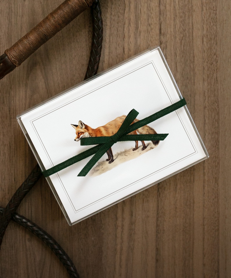 Puede incluir: Un juego de tarjetas de felicitaci&oacute;n en blanco con una ilustraci&oacute;n de un zorro y una cinta verde. Las tarjetas est&aacute;n empaquetadas en una funda de pl&aacute;stico transparente.