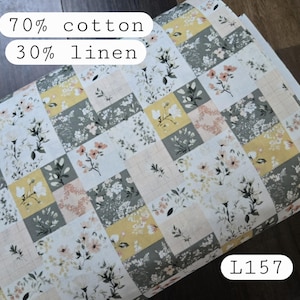 May include: A fabric with a patchwork design featuring floral patterns in white, yellow, gray, and peach. The fabric is composed of 70% cotton and 30% linen. The product code is L157.