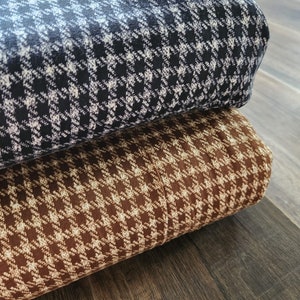 May include: Two rolls of fabric with a houndstooth pattern. The top roll is black and white, and the bottom roll is brown and white.