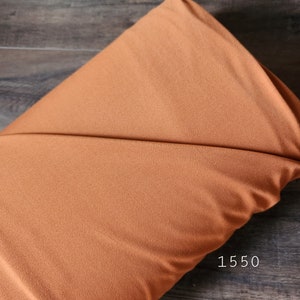 May include: A close-up of a soft, brown fabric backdrop. The fabric has a subtle texture and is perfect for photography.