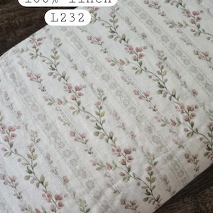 May include: A roll of off-white fabric featuring a repeating vertical pattern of delicate pink flowers and green leaves on thin stems. The fabric is labeled with the text stonewashed, 100% linen, and L232. The material has a visible woven texture.