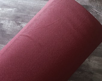 May include: A roll of burgundy fabric with a textured, woven pattern. The fabric is tightly rolled, revealing its thickness and the intricate design. The number "1640" is visible in the lower right corner.