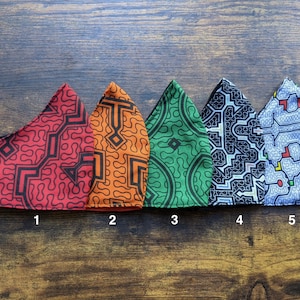 May include: Five fabric face masks with geometric patterns in red, orange, green, black, and blue. The masks are numbered 1 through 5.