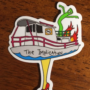 May include: A white boat with a red railing and a green inflatable person on top. The boat is on fire and has the words "The Implication" written on the side. The boat is on a pair of yellow legs with red high heels.