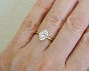 May include: A gold band engagement ring with a large oval-shaped diamond.