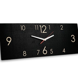 May include: A black rectangular clock with white hands and gold numbers. The clock face has a brushed metal finish.