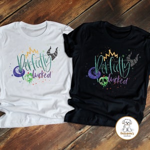 K&ouml;nnte beinhalten: Zwei T-Shirts, eines wei&szlig; und eines schwarz, mit dem Text "Perfectly Wicked" in gr&uuml;ner und lila Schrift. Die Shirts zeigen eine Krone, H&ouml;rner und eine Grafik mit einem vergifteten Apfel.