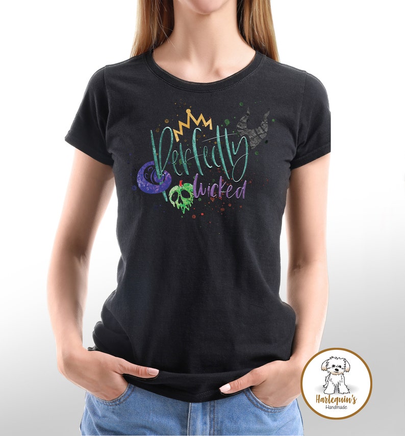 K&ouml;nnte beinhalten: Schwarzes T-Shirt mit einer gr&uuml;nen, violetten und goldenen Grafik, auf der "Perfectly Wicked" mit einer Krone, einem Apfel und einem Horn steht.