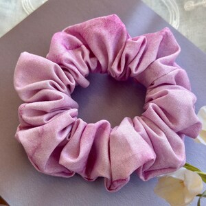 May include: A soft, purple fabric scrunchie with a tie-dye pattern.