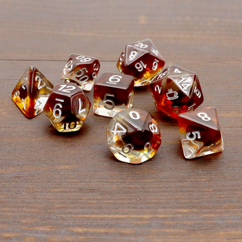 May include: A set of eight brown and clear dice with white numbers. The dice are scattered on a wooden surface.