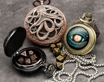 Puede incluir: Dos relojes de bolsillo antiguos con cadenas, uno con un diseño de pulpo y el otro con un ojo verde, rodeados de dados.