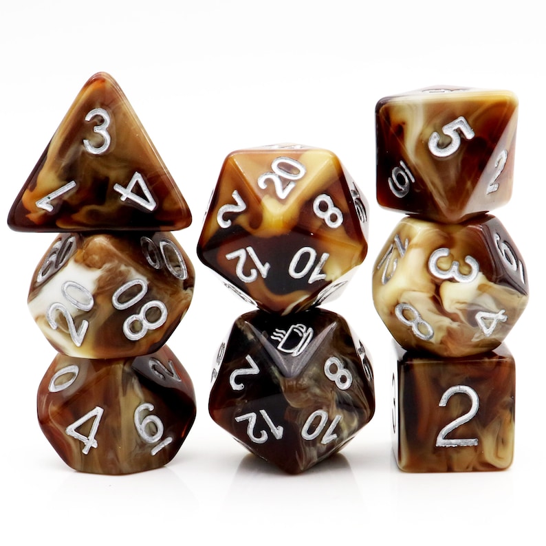May include: Set of seven brown and white marbled dice with silver numbers. The dice are in a stack of three, two, and two. The dice are for role-playing games.