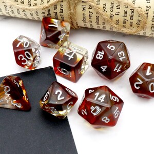 May include: A set of eight brown and clear dice with white numbers. The dice are in various shapes, including a d4, d6, d8, d10, d12, and d20.
