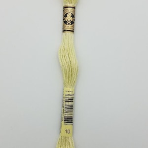 May include: A skein of pale yellow embroidery floss with a paper label featuring the DMC logo, the number 25, and a length of 8 meters or 8.7 yards. The lower label displays a barcode and the number 10, indicating the specific color shade.