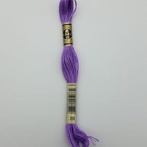 May include: A skein of purple embroidery floss with a paper label featuring the DMC logo, the text 25, 8m (8.7 yd), a barcode, and the number 209. The thread is wound into a long, twisted bundle with loose ends at the bottom.
