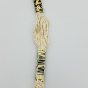 May include: A skein of off-white embroidery floss labeled ECRU. The paper band features the text MOULINE SPECIAL 25, 8m (8.7 yd), and a barcode. The thread is composed of multiple strands of cotton fiber, neatly twisted and secured by the central label.