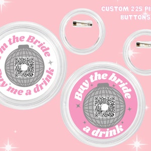 May include: Custom pinback buttons with a pink and white design. The buttons feature the text "I'm the Bride" and "Buy me a drink" around a disco ball graphic. Each button has a QR code in the center and a clear plastic casing.