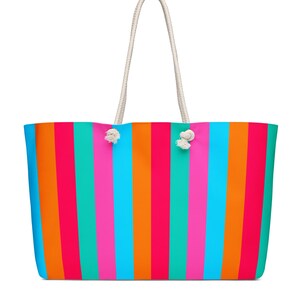 Könnte beinhalten: Eine große Tragetasche mit vertikalen Streifen in leuchtenden Farben: Pink, Orange, Türkis und Blau. Die Tasche hat weiße Seilgriffe und ist zum Tragen von Gegenständen konzipiert. Die Tasche besteht aus einem strapazierfähigen Material.