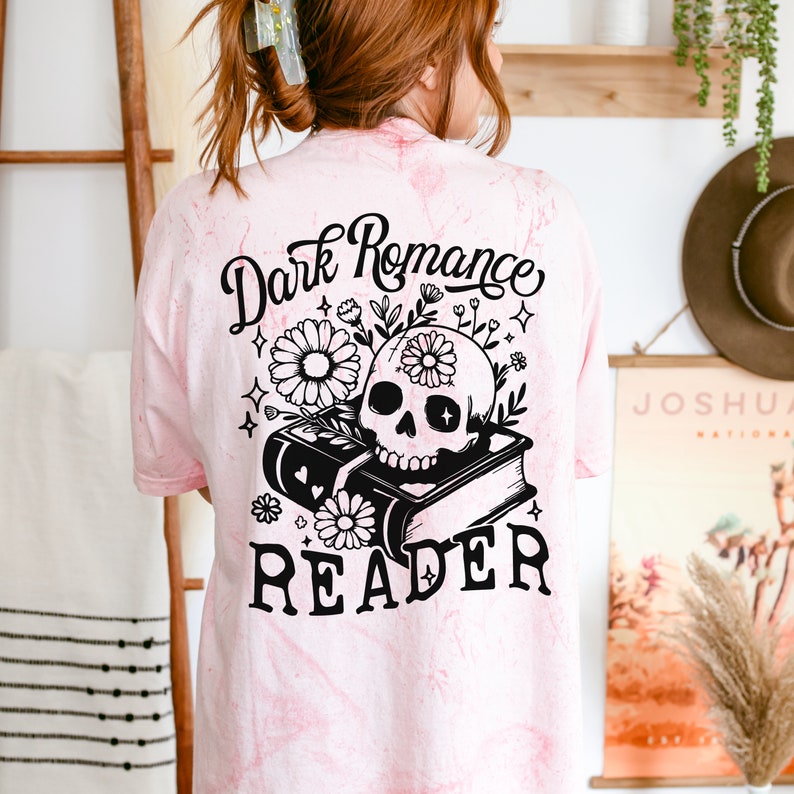 May include: Pink tie-dye t-shirt with a black graphic of a skull with flowers on top of a book. The text "Dark Romance Reader" is printed below the graphic.