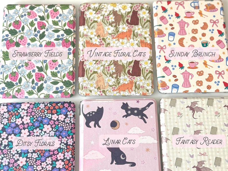 May include: Six decorative, rectangular boxes with various patterns and text labels. Designs include strawberries, cats, brunch items, floral patterns, cats with moons, and fantasy creatures. Labels read "Strawberry Fields", "Vintage Floral Cats", "Sunday Brunch", "Ditsy Florals", "Lunar Cats", and "Fantasy Reader".