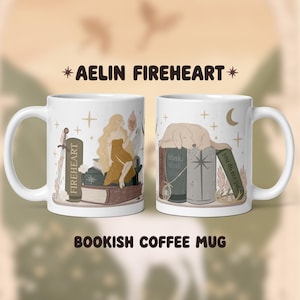 Könnte beinhalten: Zwei weiße Keramik-Kaffeetassen mit Illustrationen. Eine Tasse zeigt eine Frau in einem goldenen Kleid, die auf Büchern sitzt, die andere einen schlafenden Hund. Auf den Tassen steht "AELIN FIREHEART" und "BOOKISH COFFEE MUG".