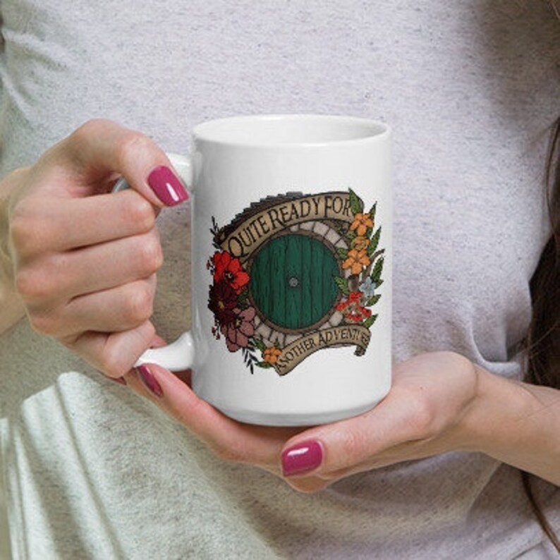 May include: White ceramic mug with a green door surrounded by flowers and the text "Quite ready for another adventure".