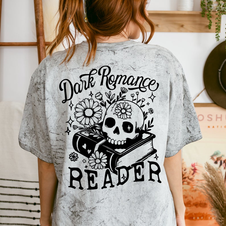 May include: A gray t-shirt with a black and white graphic design of a skull with flowers on top of a book. The text "Dark Romance Reader" is printed on the shirt.