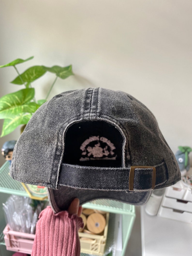 May include: Black denim baseball cap with an adjustable strap and a small embroidered logo on the back. The logo features a horse and the text "Springbrook Creek".