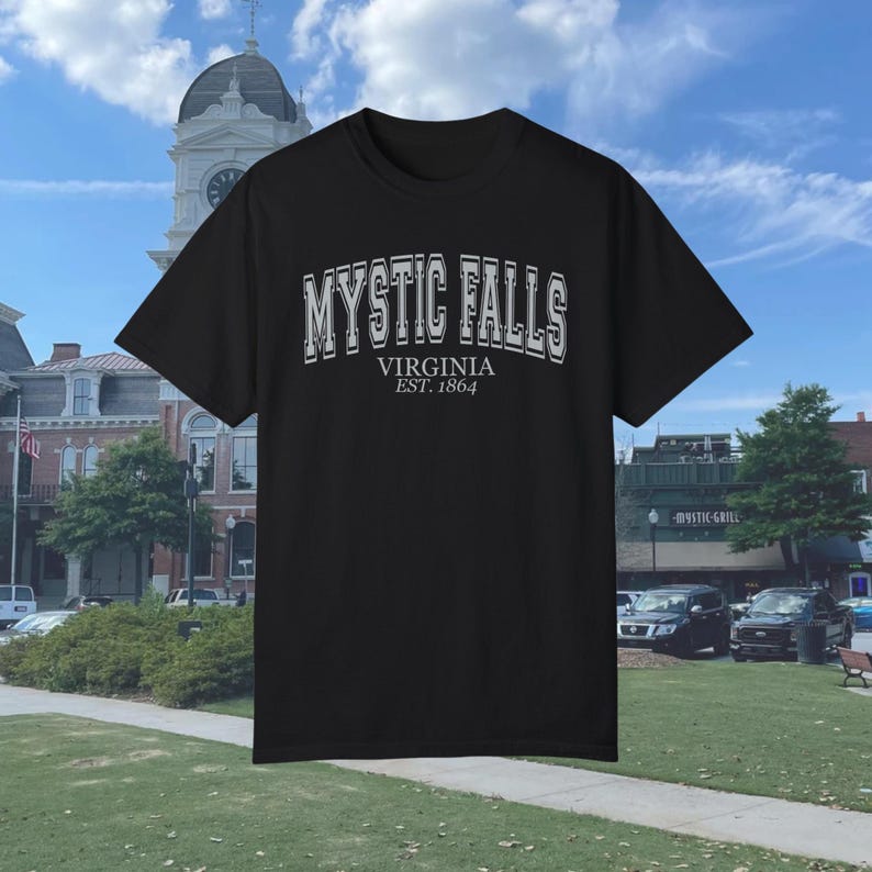 Puede incluir: Camiseta negra con un estampado gr&aacute;fico blanco que dice "Mystic Falls, Virginia Est. 1864".