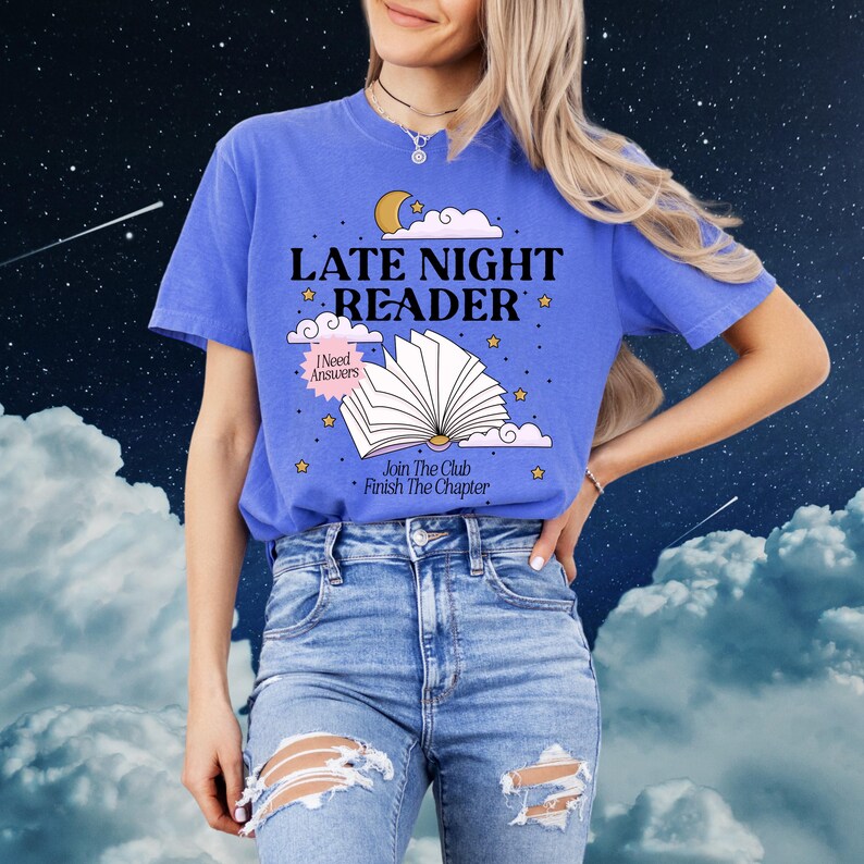 May include: A blue t-shirt with the words "LATE NIGHT READER" in white, along with an illustration of an open book, moon, and stars. The shirt also has the phrases "I Need Answers" and "Join The Club Finish The Chapter".