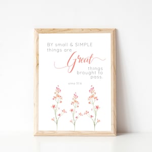 May include: A framed print with a white background and a quote in black text: "BY small & SIMPLE things are Great things brought to pass. alma 37:6". The quote is written in a cursive font. The print is decorated with three watercolor illustrations of pink and orange flowers.