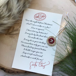 Puede incluir: Una tarjeta blanca con un poema sobre Papá Noel que ha perdido un botón. El poema dice: "Twas the night before Christmas, And I ate a cookie or a few! Now it appears I have lost my button too! It may be by the front door Or under the tree. It may be in your stocking, Or somewhere only you can see. Please find my special button. It holds magic you see. Keep it safe and sound And make a wish for me!" La tarjeta está firmada "Santa Claus".