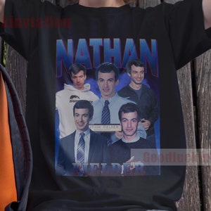 May include: A black t-shirt with a graphic print of a group of men with the text "NATHAN FIELDER" and "FUEL DERR" in blue and red letters.