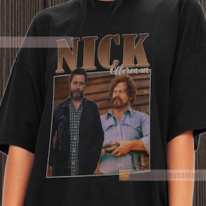 May include: Black t-shirt featuring a vintage-style graphic of Nick Offerman. The graphic includes a photo of Nick Offerman and another man, with the text "NICK Offerman" in a brown box.