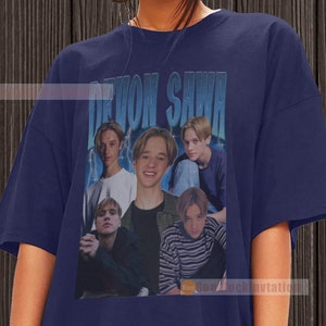 May include: A navy blue t-shirt with a vintage-style graphic of a band called "Devon Sawa". The graphic features five young men with blonde hair.