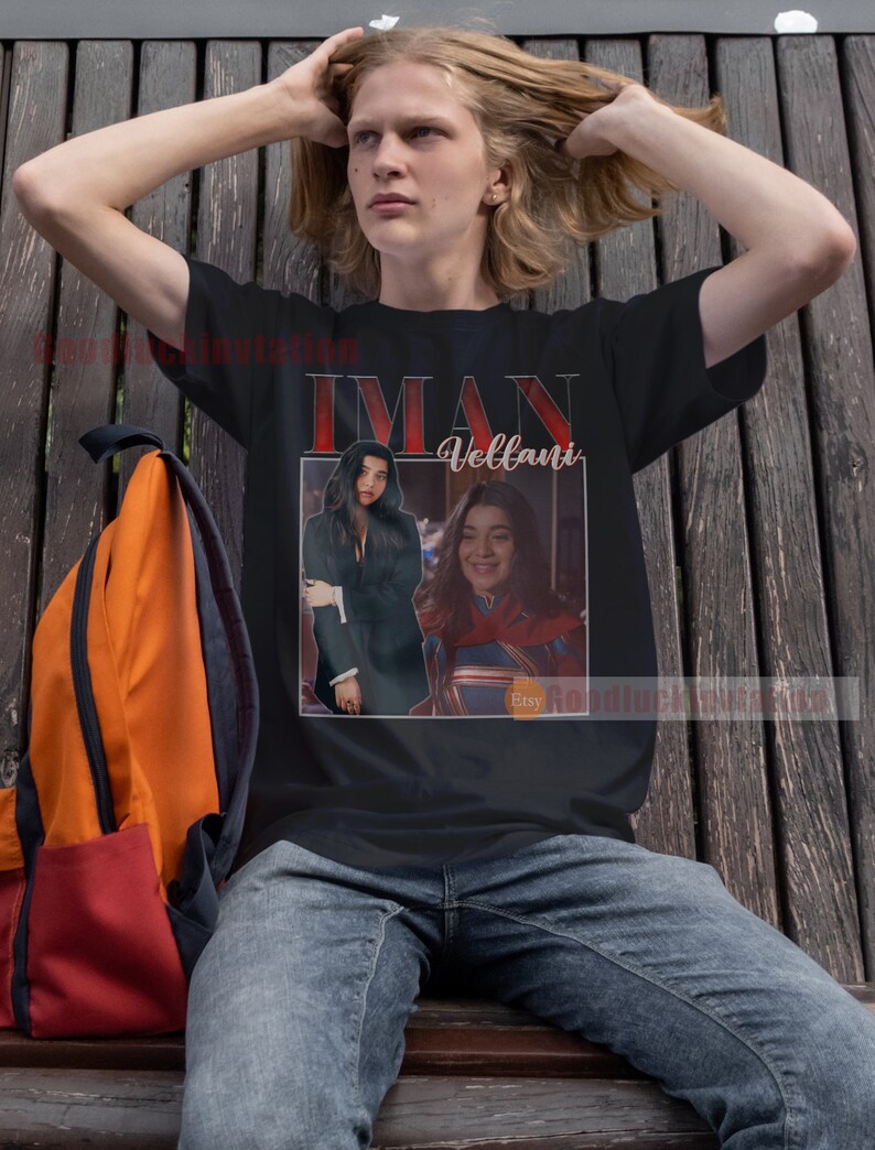 May include: A black t-shirt featuring a retro-style graphic of Iman Vellani as Kamala Khan, the superhero Ms. Marvel. The graphic is in a white frame with red text that says "Iman Vellani".