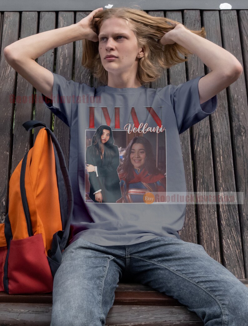 May include: A grey t-shirt featuring a graphic of a woman with long dark hair and a woman with short brown hair. The text "Iman Vellani" is printed on the shirt.