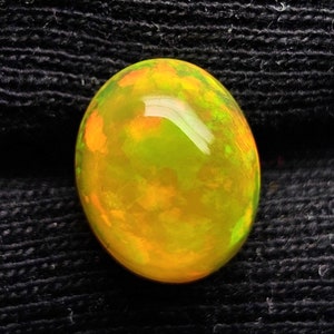 May include: A bright yellow oval opal gemstone with orange and green flashes of color.