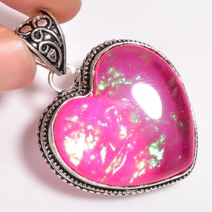 May include: A silver heart-shaped pendant with a pink iridescent stone. The pendant has an ornate silver bail.