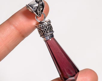 Puede incluir: Un colgante de plata con una piedra preciosa de amatista púrpura. El colgante tiene forma de lágrima y tiene una baíl de plata detallada.