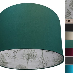 May include: A teal lampshade with a white and green floral pattern on the inside. The lampshade is made of fabric and has a round shape.