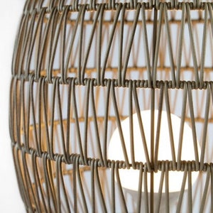 May include: A close-up of a woven wicker pendant light fixture with a white light bulb inside.